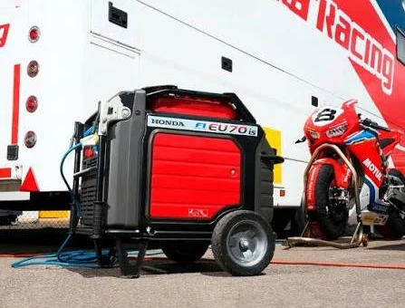 Generador insonoro junto a un camión de equipo y una motocicleta de competición
