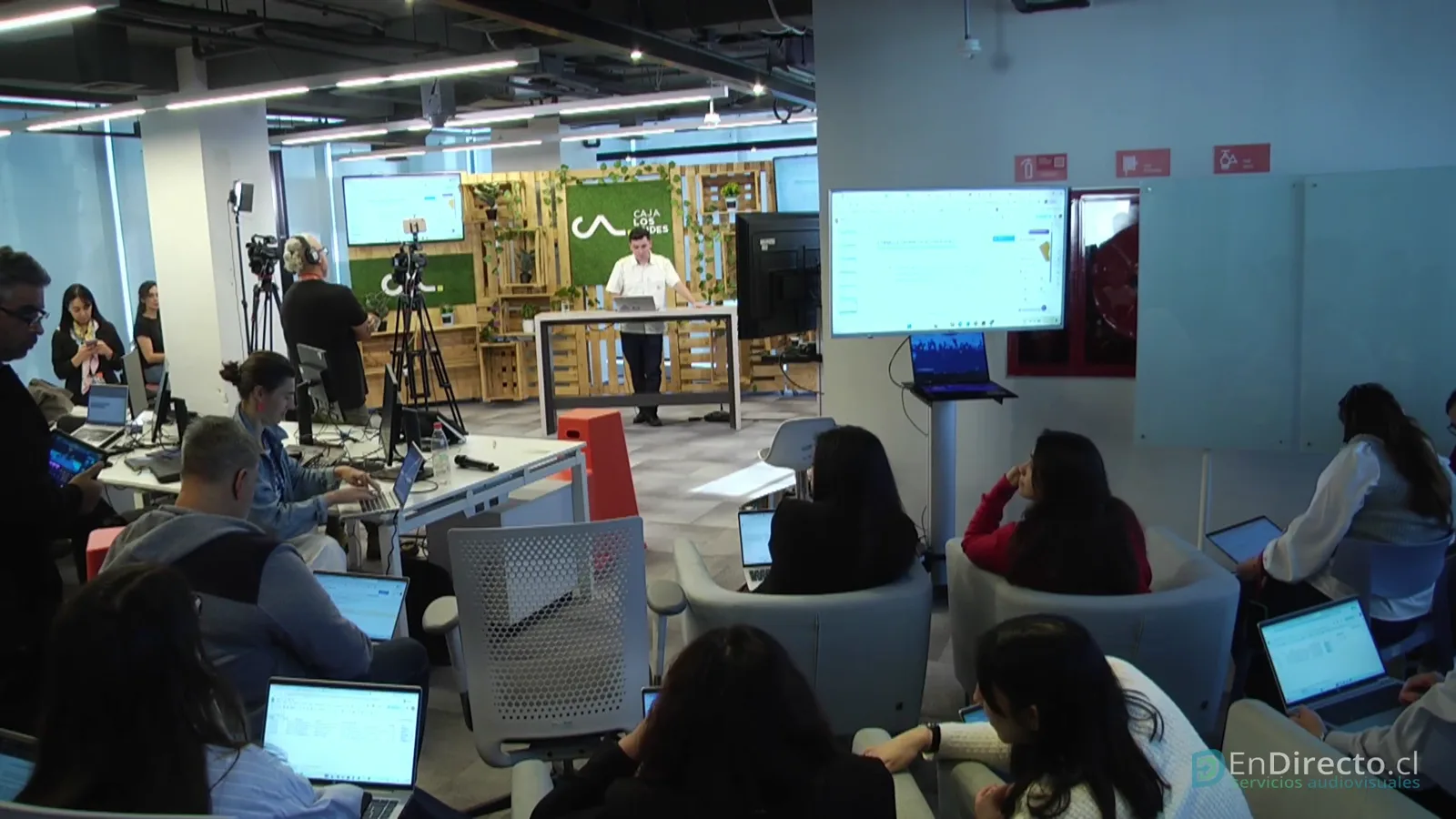 Asistentes con sus notebooks durante el taller, con el set y las cámaras al fondo