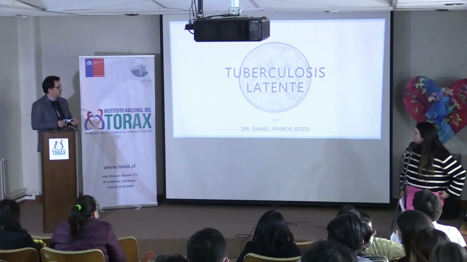 Plano general del auditorio con el podio y la pantalla del curso
